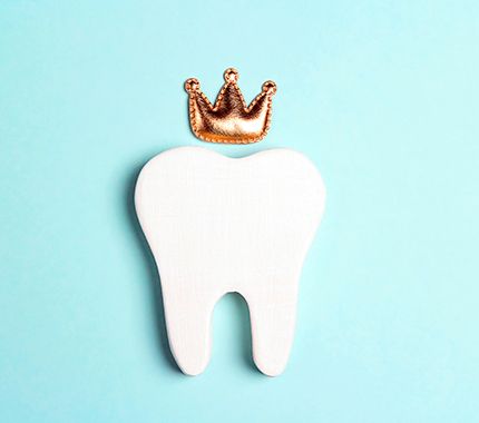 Fake wooden tooth with crafted crown on a pale teal background