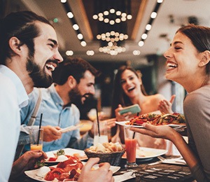 Group of friends smiling while eating at restaurant